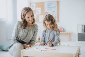 Une petite fille et une sophrologue dessine sur papier ensemble